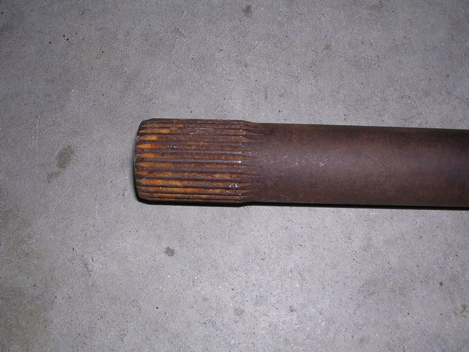 Rusted axle shaft with splines on a concrete surface