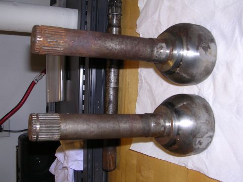 1983 Ferrari Enzo - Two rusty axle shafts are shown, each with splined ends and spherical joints, suggesting they are automotive parts.