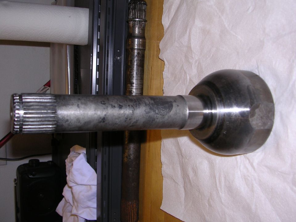 CV axle shaft with splines on one end and a ball joint housing on the other