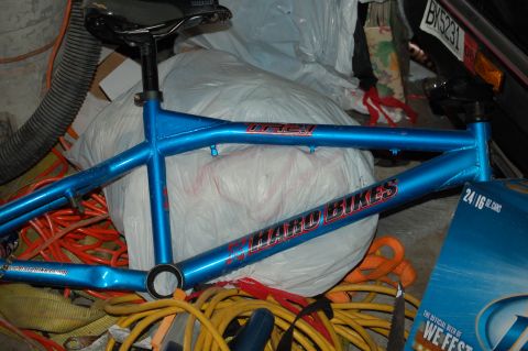 1991 Ford Escort - A blue bicycle frame with visible branding and some denting is stored with various cords and a plastic-wrapped object.