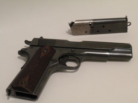 1996 Ford Bronco - A Colt M1911 pistol and its magazine are displayed on a flat surface.