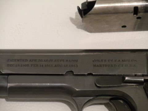 1996 Ford Bronco - Close-up of a Colt pistol slide showing patent dates and manufacturer information, with a magazine visible at the top.
