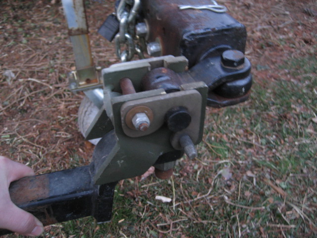 Detail of olive-drab pintle coupler jaw engaging rusty pintle hook on receiver bar