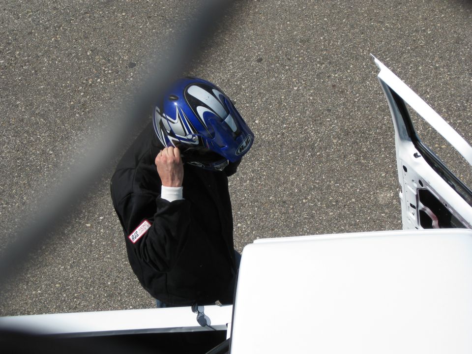 Person in blue and silver helmet adjusting helmet, standing next to a white vehicle with door open. Supermotors.net logo visible