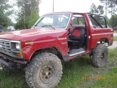 1983 Ford Bronco - This red Ford Bronco, modified for off-road use, is viewed from a three-quarter front angle.