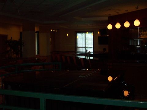 1985 Ford Bronco - Dimly lit interior scene with a dark, reflective surface in the foreground and blinds on a window in the background.
