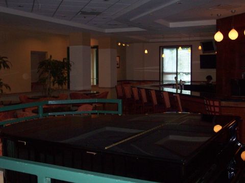 1985 Ford Bronco - The interior of a hotel lobby features a grand piano in the foreground and a bar with seating in the background.