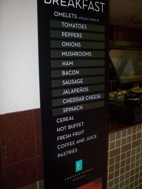 1985 Ford Bronco - A sign displays the breakfast offerings at an Embassy Suites hotel, including omelet choices and other breakfast items.