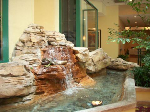 1985 Ford Bronco - An indoor waterfall feature with artificial rocks and a small pool is visible in a hotel lobby area.