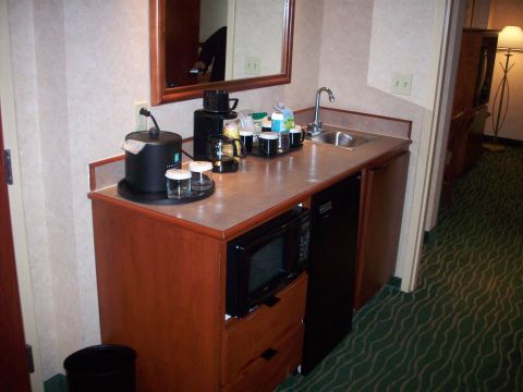1985 Ford Bronco - A hotel room kitchenette area features a coffee maker, microwave, sink, and mini-fridge, with a mirror above the counter.