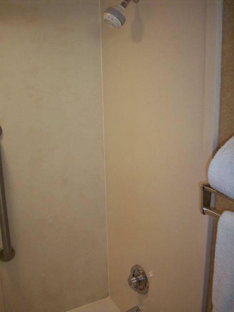 1985 Ford Bronco - A hotel bathroom shower stall is shown with a grab bar on the left and towels on a rack to the right.