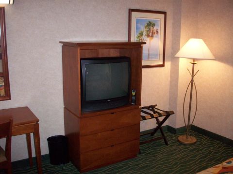 1985 Ford Bronco - A hotel room scene a television, a luggage rack, and a floor lamp.