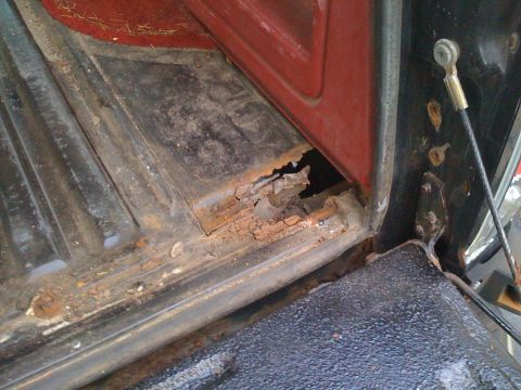 1988 Ford Bronco - Severe rust damage is visible on the interior floor and door jamb of this vehicle.