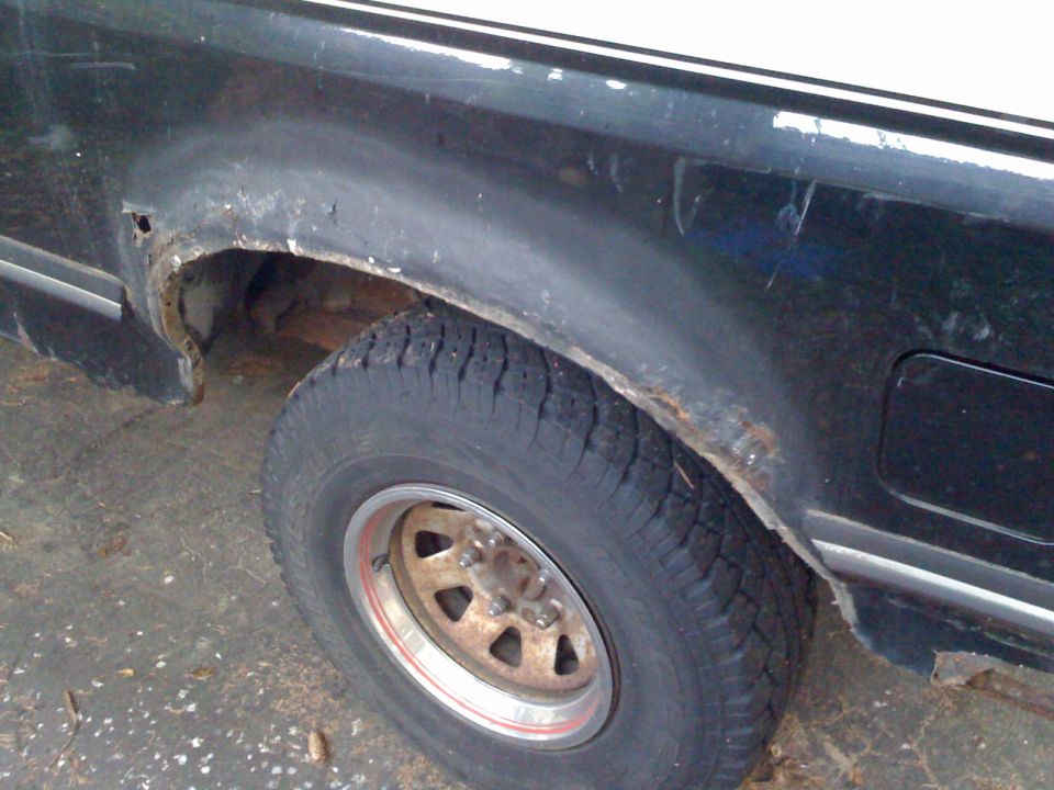 1988 Ford Bronco rear wheel well showing significant rust damage and a worn tire