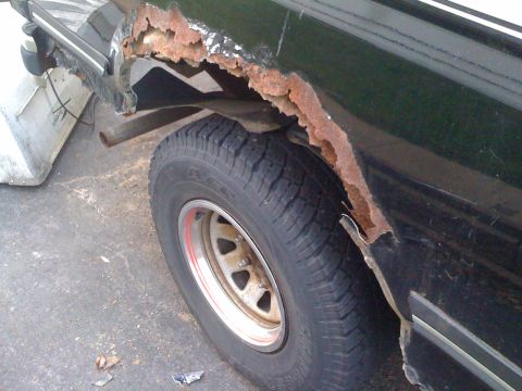 1988 Ford Bronco - The rear wheel well of the vehicle shows extensive rust and deterioration.