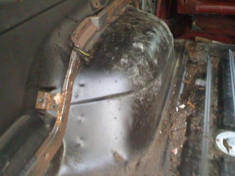 1988 Ford Bronco - Close-up view of the interior wheel well and floor area, showing signs of rust and accumulated debris.