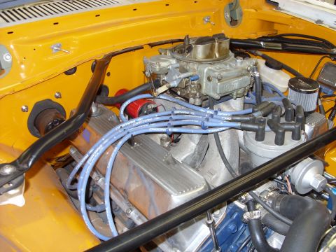 1978 Ford Mustang II - Overhead view of a small-block V8 in a bright orange engine bay, fitted with a Holley carburetor on an aluminum intake, finned aluminum val…