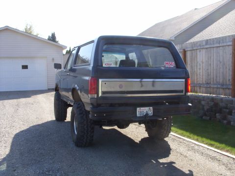 1988 Ford Bronco - Rear view of a dark 1988 Ford Bronco, modified with a lifted suspension and oversized tires.