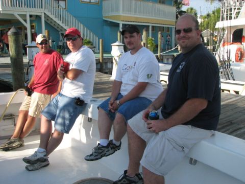 1979 Ford F-150 - Four men relax on a boat, with a waterfront building and dock visible behind them.