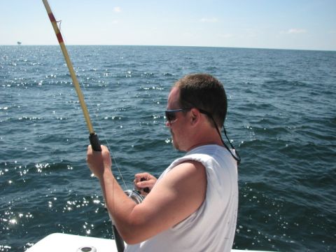 1979 Ford F-150 - A man casts his fishing line into the sparkling blue ocean from the deck of a boat.