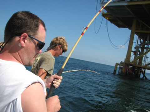1979 Ford F-150 - Two men enjoy a day of fishing from a boat, with an offshore oil rig visible in the background.
