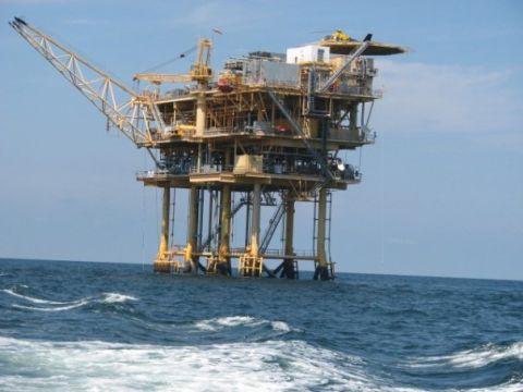 1979 Ford F-150 - An offshore oil rig stands tall in the water under a clear blue sky.