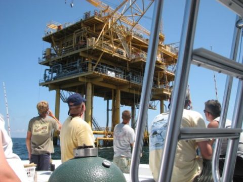 1979 Ford F-150 - People on a boat observe an offshore oil rig under a clear blue sky.