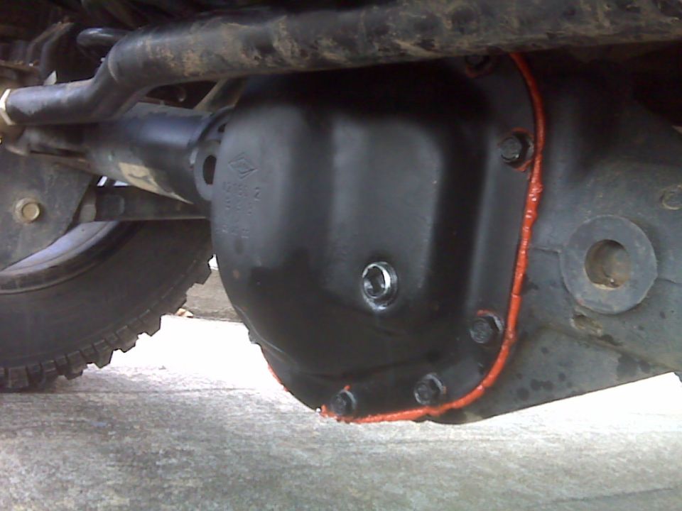 Differential cover bolted on with red RTV sealant squeeze-out around the flange