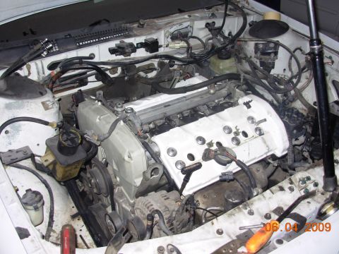 1995 Ford Taurus - The engine bay of a white vehicle is shown with various mechanical parts and wiring.