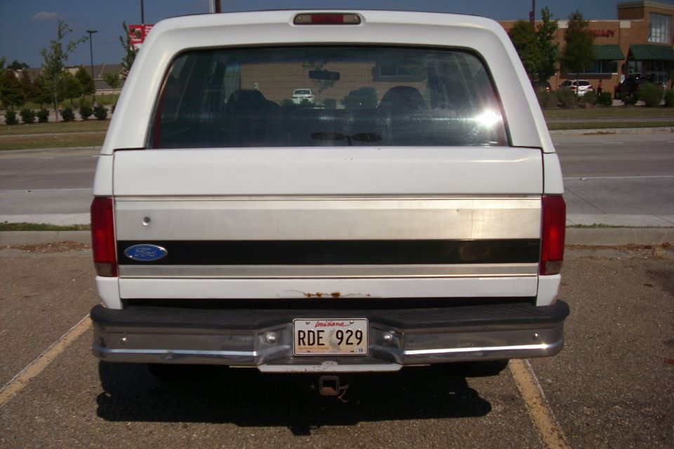 Rear view of a white 1995 Ford Bronco with a license plate that reads RDE 929