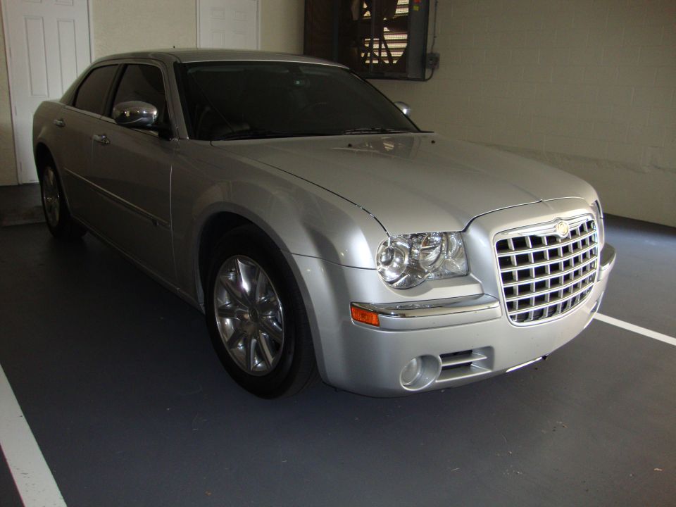 Silver Chrysler 300 front three-quarter view with chrome grille and fog lights in a garage