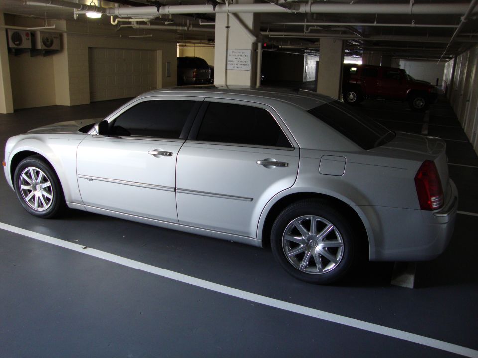 Silver Chrysler 300 parked in a garage. Another vehicle is visible in the background