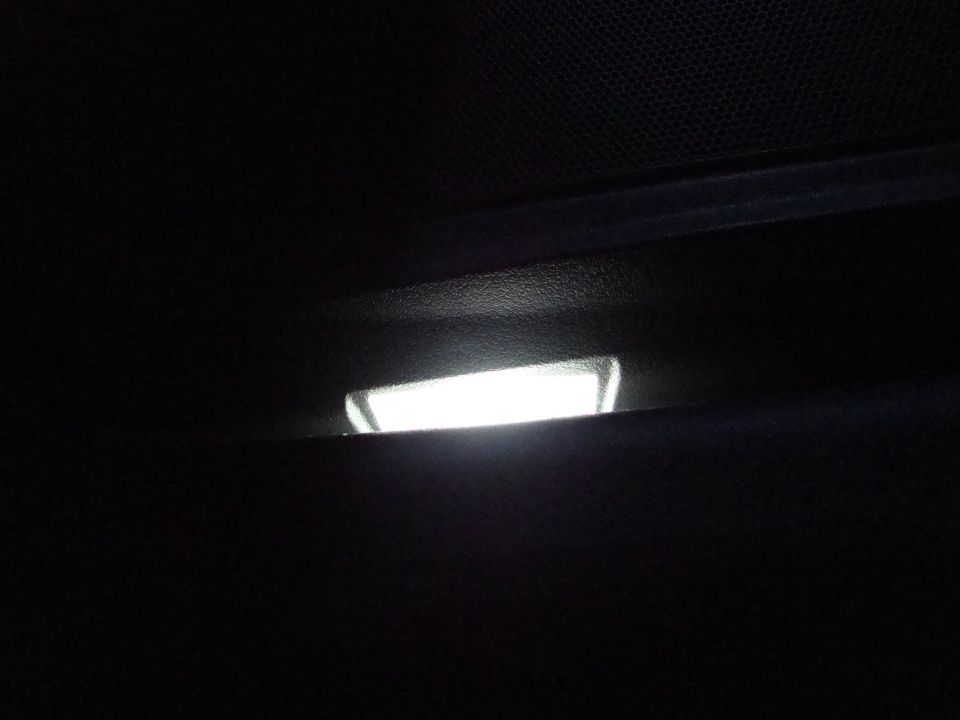 Interior overhead light illuminated in a dark car cabin. Supermotors.net logo visible