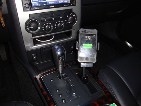 2008 Chrysler 300 - The interior of a car shows a center console with an iPhone mounted in a holder, charging.