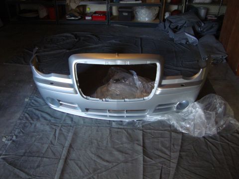 2008 Chrysler 300 - Front bumper and grille assembly for a Chrysler 300, possibly from the mid-2000s, is laid out on a dark tarp.