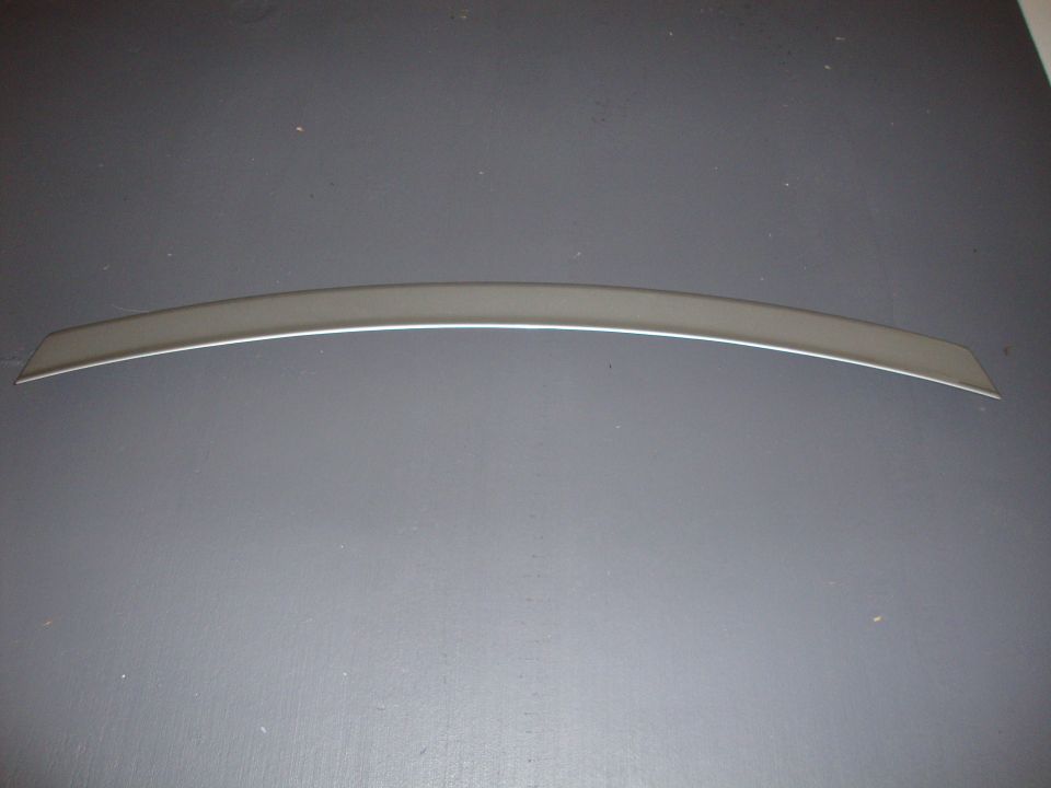 Curved chrome trim piece with a beveled edge, resting on a gray surface