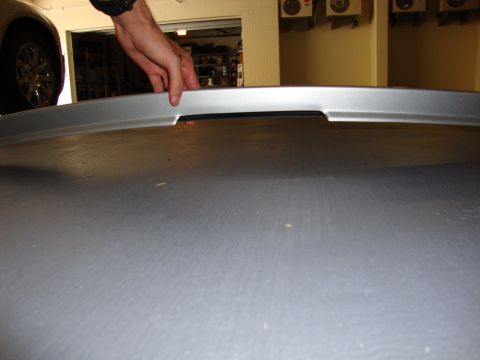 2008 Chrysler 300 - A silver rear spoiler part is being held by hands.