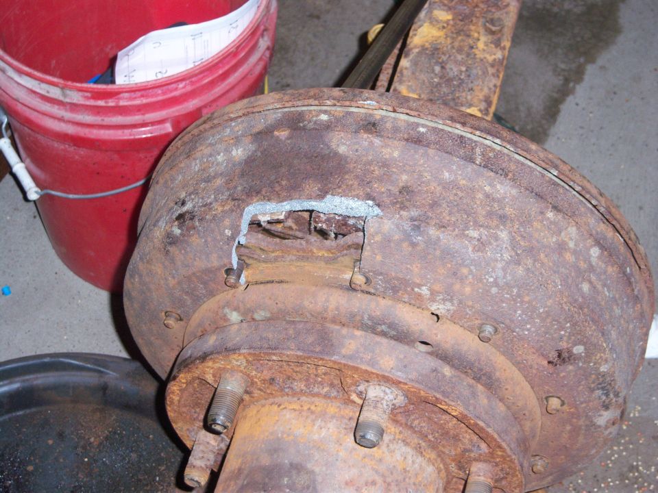 Rusty brake drum assembly with a hole showing internal components