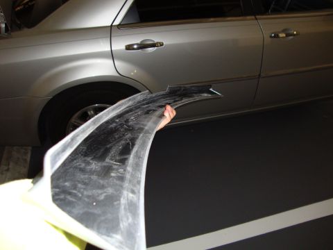 2008 Chrysler 300 - A person holds a detached black trim piece next to the rear fender and door of a silver Chrysler 300.