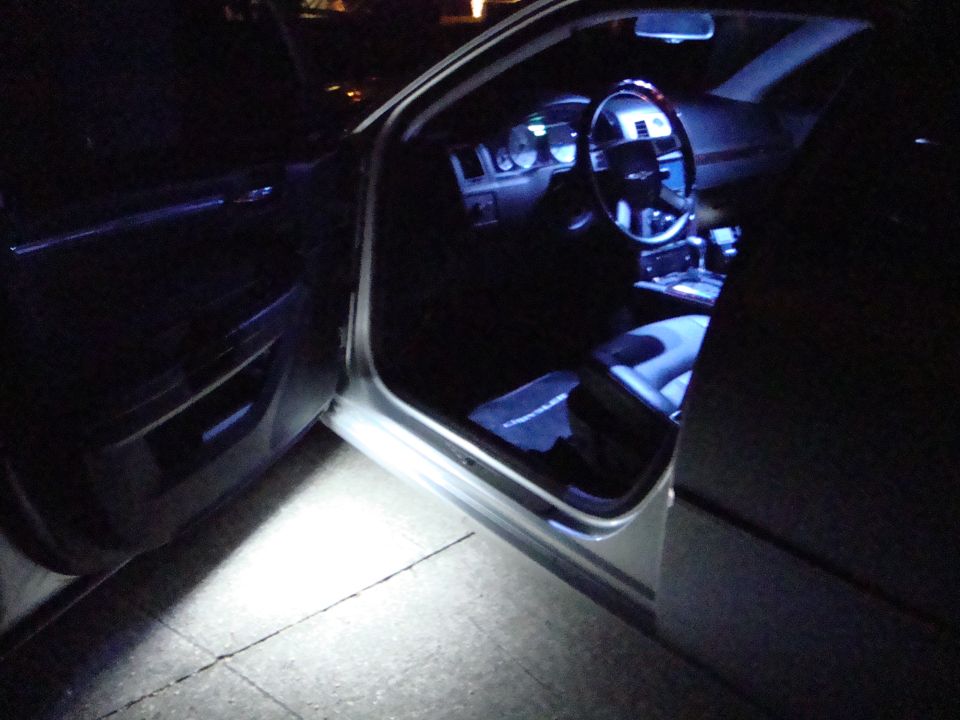 Chrysler sedan driver's door open at night with white LED interior and puddle lighting