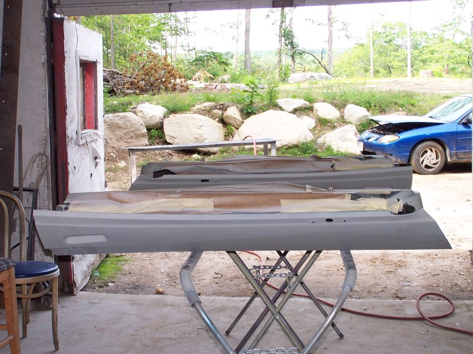 Two primer-gray vehicle panels on a stand in an open garage door
