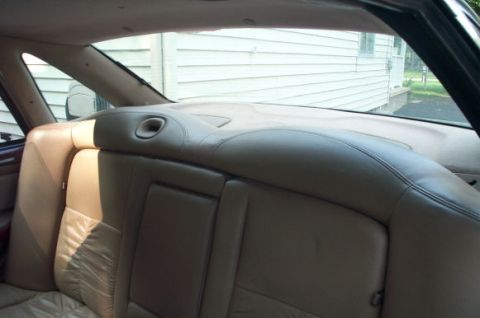 1995 Ford Taurus - Interior view of tan leather rear seats in a car, with a house seen through the window.