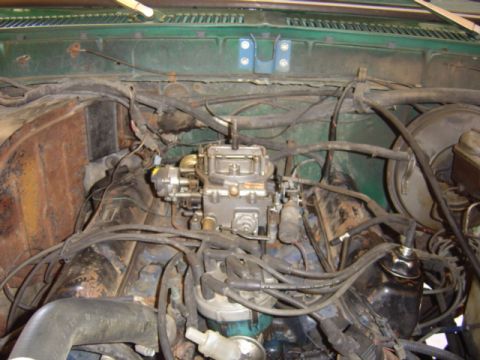 1979 Ford Bronco - Close-up of a vehicle's engine bay, focusing on the carburetor and associated components.