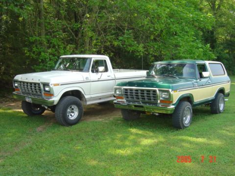 1979 Ford Bronco - Two vintage Ford trucks, a pickup and a Bronco, are parked side-by-side on a grassy area.