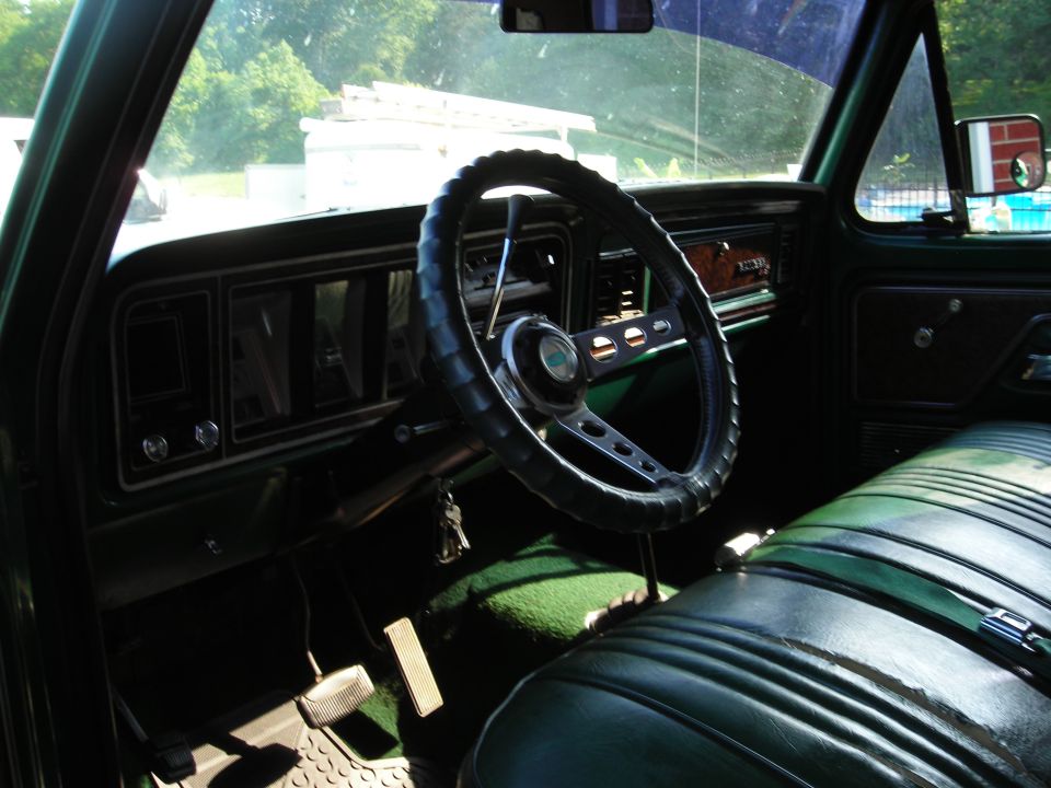 Green 1979 Ford Bronco interior with a black steering wheel and dark green bench seat