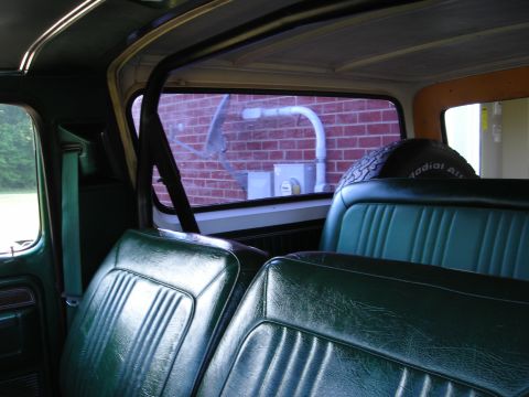 1979 Ford Bronco - Interior view of a green vehicle, showing the bench seats and a spare tire mounted behind them.