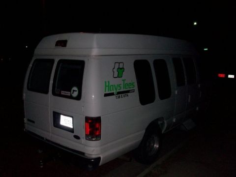 2006 Ford E250 - Rear view of a white van with tinted windows and a company logo on its side.