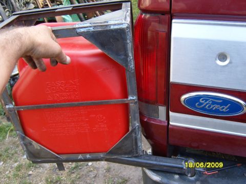 1989 Ford Bronco - A red Ford truck's rear is shown with a custom metal rack holding a red jerrycan, indicating a possible older model year.