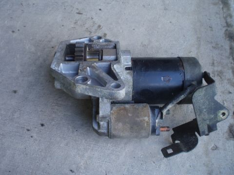 1993 Ford Probe - A starter motor assembly, likely for a vehicle, is shown resting on a concrete surface.