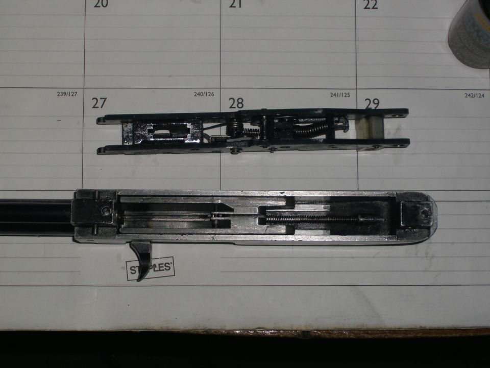 Disassembled metal action with springs and trigger laid on a desk calendar